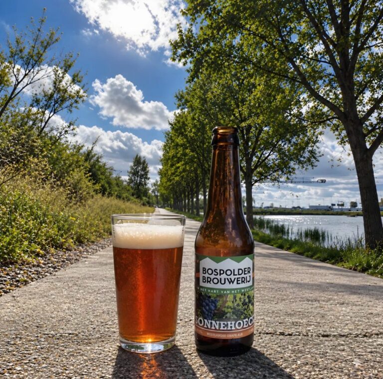 Sonnehoeck Grape Ale van Bospolder Brouwerij, glas en fles op een fietspad langs het water bij de Wollebrand in Honselersdijk