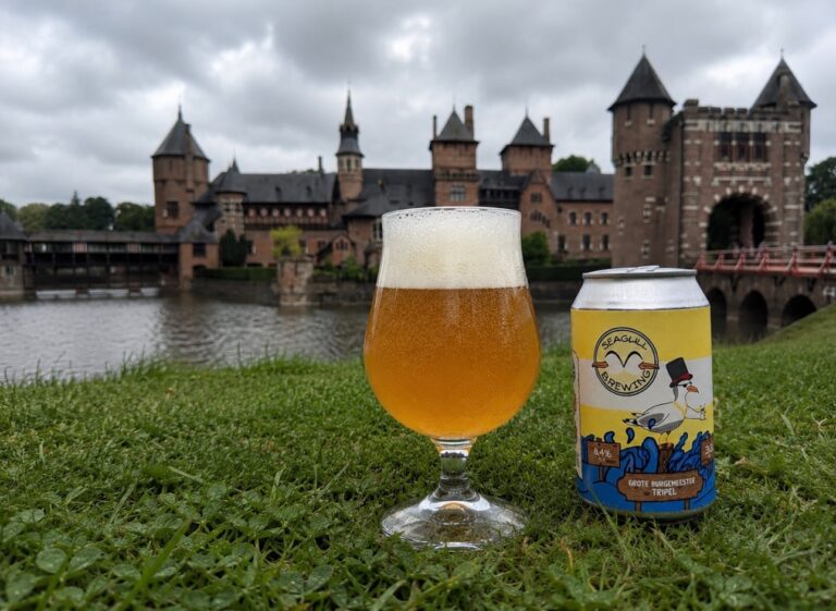 Grote Burgemeester Tripel van Seagull Brewing, glas en blik in het gras aan de gracht van een kasteel