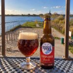 Strooplikker Bock van De Poel, glas en fles op een tafel op Papeneiland met uitzicht over de Langeraarse Plassen